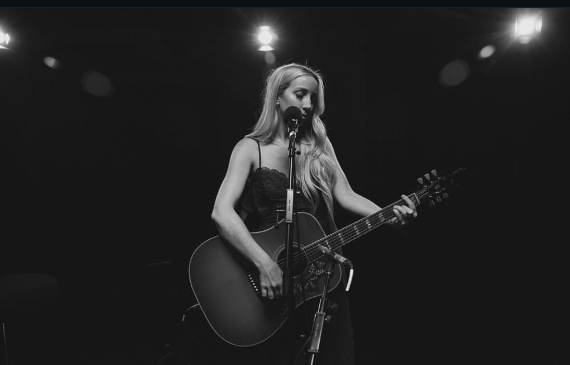 Artist performing live with an acoustic guitar